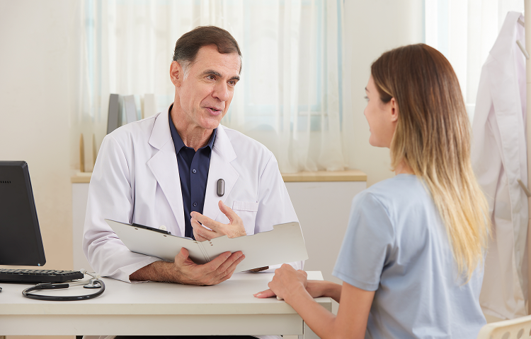 Doctor wearing a dark gray Plaud NotePin on his lab coat during a consultation with a patient.