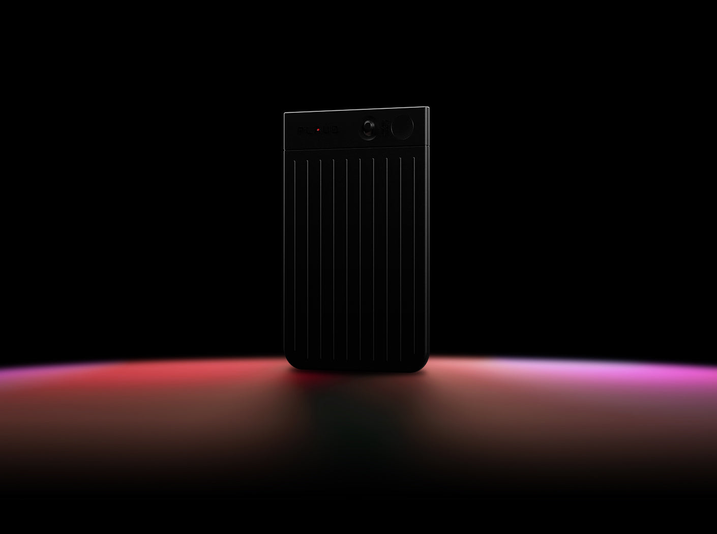 Black Plaud Note Pro standing upright on a dark surface with red and purple light reflections.
