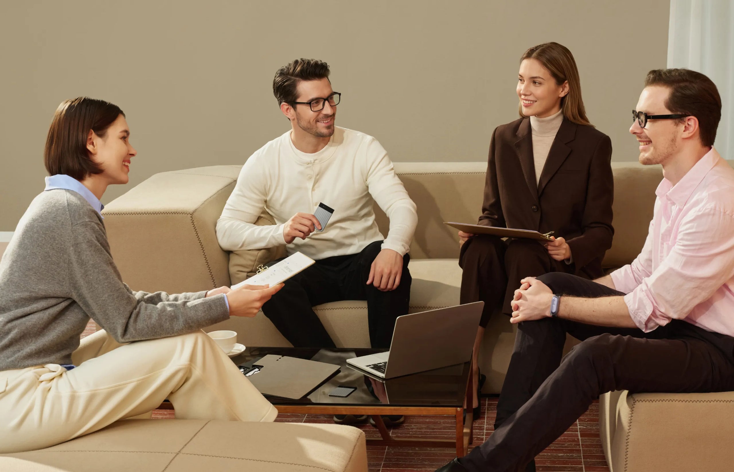 Four colleagues in a casual meeting, one man holds a dark Plaud Note, capturing their discussion.