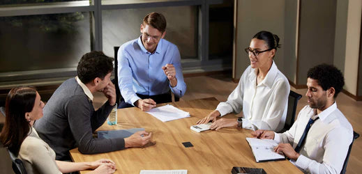 Five professionals in a meeting, with a white Plaud Note Pro on the table capturing discussion.