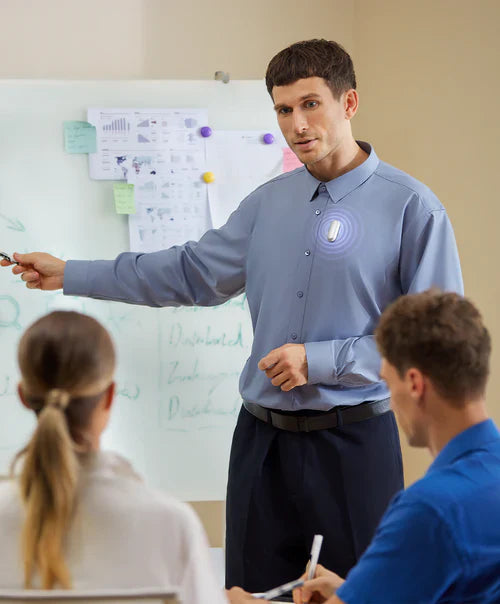 Man presenting in a meeting with a white Plaud NotePin on his shirt, actively recording the discussion.