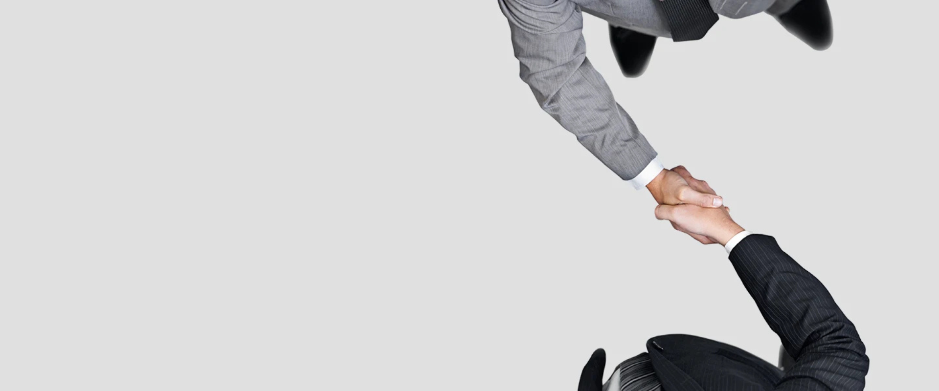 Two business people in suits shaking hands, viewed from above, symbolizing partnership or agreement.
